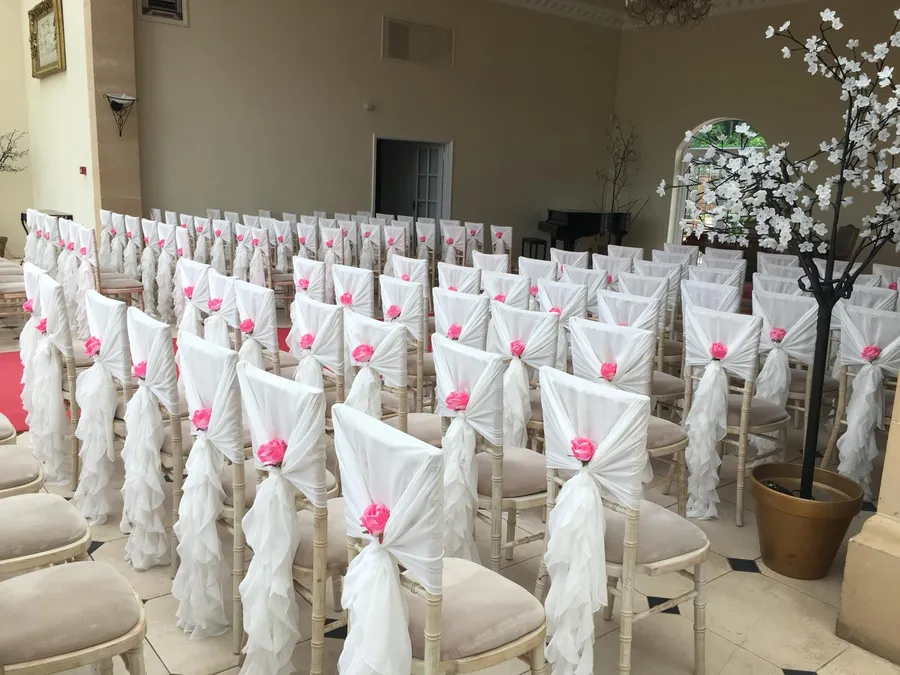 Limewash Chiavari chairs with ivory chiffon ruffle hoods and hot-pink roses